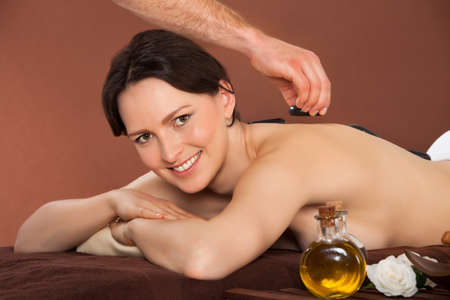 Portrait of beautiful young woman receiving hot stone therapy in spaの写真素材
