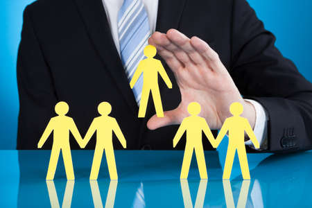 Midsection of businessman holding paper people representing recruitment against black backgroundの写真素材