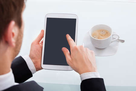 Cropped image of businessman holding digital tablet at desk in office