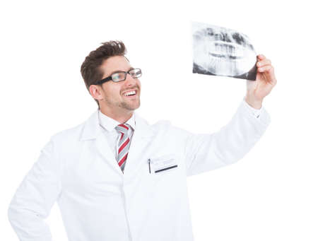 Smiling young male doctor examining dental x-ray over white backgroundの写真素材