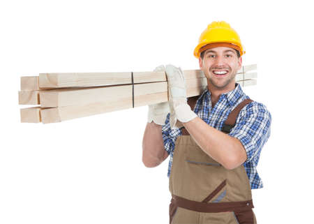 Full length portrait of young manual worker carrying wooden planks over white background