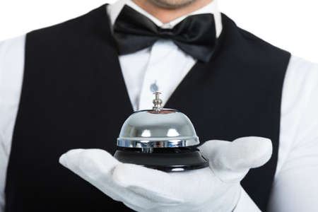Midsection of young butler holding service bell over white backgroundの写真素材