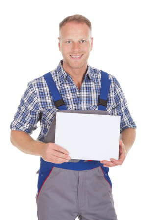 Portrait of smiling mid adult handyman holding blank placard over white backgroundの写真素材