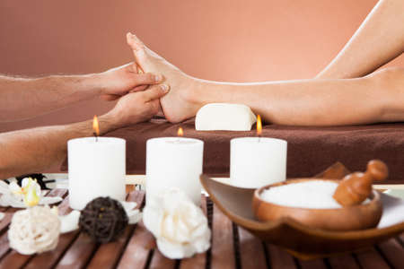 Cropped image of male therapist massaging female customer's foot at beauty spaの写真素材