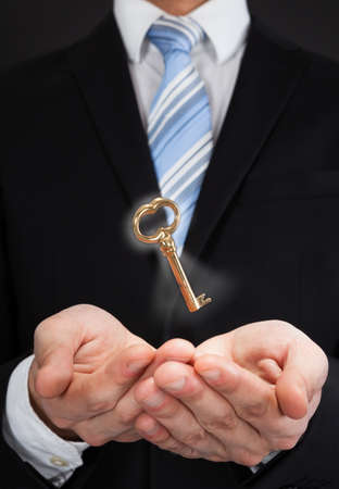 Midsection of businessman with key in midair representing successの写真素材