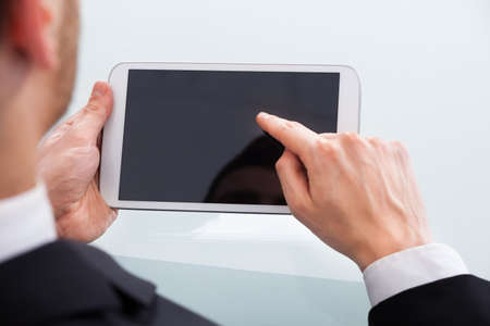 Cropped image of businessman holding digital tablet at desk in office
