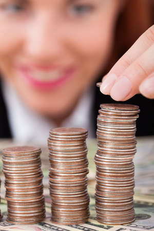 Cropped image of businesswoman stacking coins as bar graph at deskの写真素材