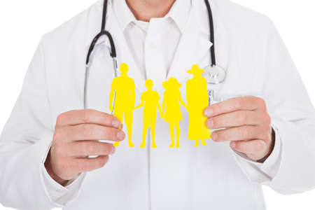 Midsection of male doctor holding paper chain family over white backgroundの写真素材