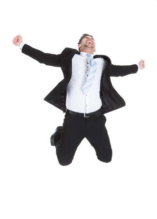 Full length portrait of young businessman celebrating success over white の写真素材