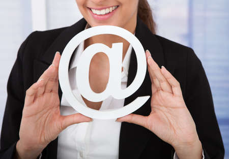 Midsection of young businesswoman holding internet symbol in officeの写真素材