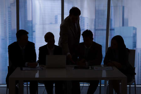 Silhouette of businessmen and businesswomen discussing in officeの写真素材