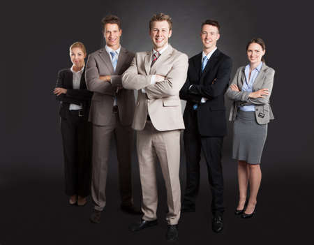 Full length portrait of confident business team standing arms crossed against black の写真素材