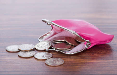 Closeup of coins spilled from pink purse on tableの写真素材