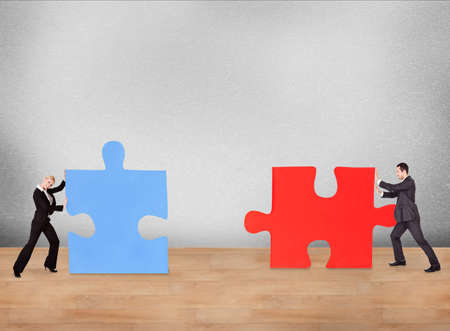 Business people joining puzzle pieces on deskの写真素材