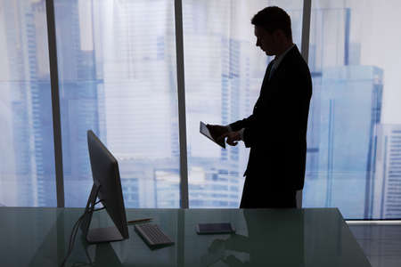 Side view of young businessman using digital tablet at desk in officeの写真素材