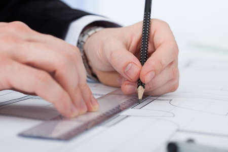Cropped image of businessman working on blueprint at desk in office