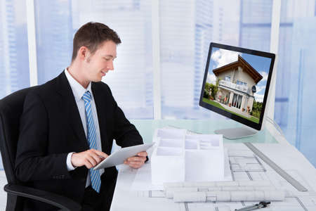 Side view of young male architect browsing property on computer in office