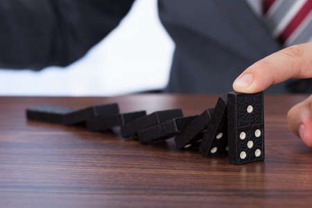 Midsection of businessman playing domino on deskの写真素材