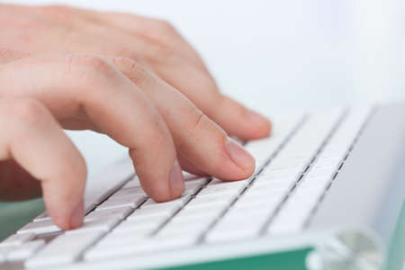 Closeup of man's hands typing on computer keyboard