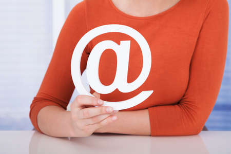 Midsection of young woman holding internet symbol at deskの写真素材