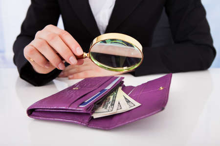 Midsection of businesswoman putting American banknotes in wallet at office deskの写真素材