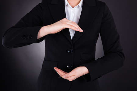 Midsection of young businesswoman with hands open isolated over black の写真素材