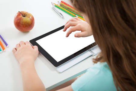 Cropped image of schoolgirl using digital tablet with blank screen at table