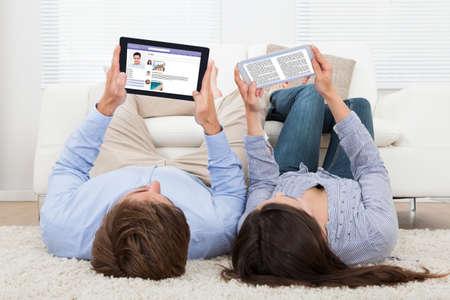 Couple lying on floor while using technologies at home