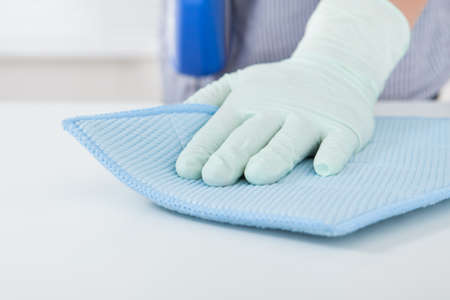 Closeup of woman's hand wiping table with rag at home