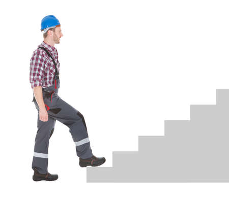 Full length side view of manual worker walking over white backgroundの写真素材