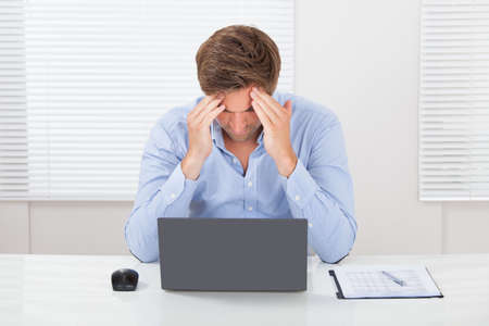 Mid adult businessman suffering from headache in office