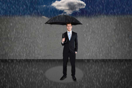 Full length of businessman holding umbrella under rainの写真素材