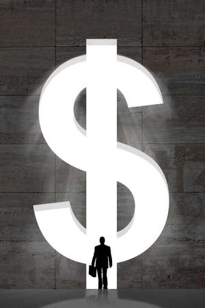 Silhouette businessman standing in front of large dollar sign in wallの写真素材