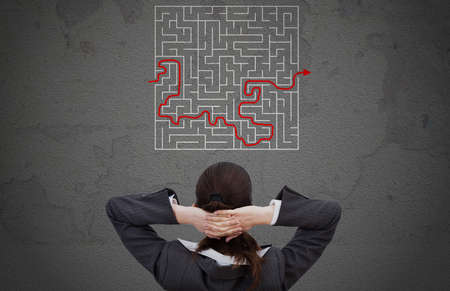 Rear view of businesswoman looking at solved maze drawn on wallの写真素材