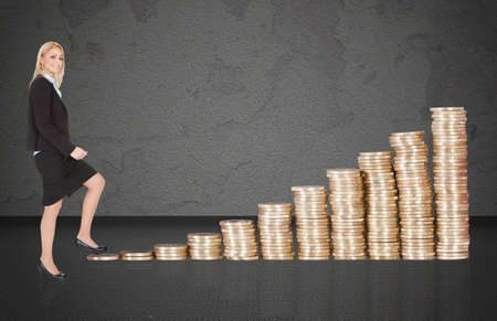 Full length portrait of confident young businesswoman climbing up stacked coins representing growthの写真素材