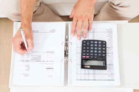 High angle view of man calculating home finances at tableの写真素材