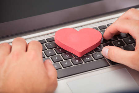 Cropped image of man dating online with heart shape on laptopの写真素材