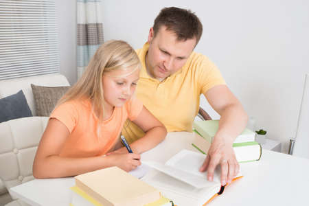 Father Helping Daughter With Homework At Homeの写真素材