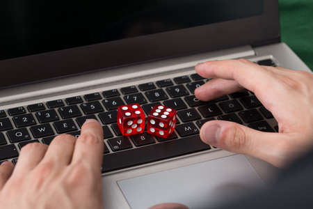 Close-up of red game dices on laptop with hands in backgroundの写真素材