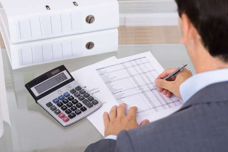 Business man accountant calculating invoices in office Business man accountant calculating invoices in office