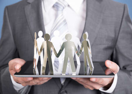 Businessman holding paper people on tablet. Closeup shotの写真素材