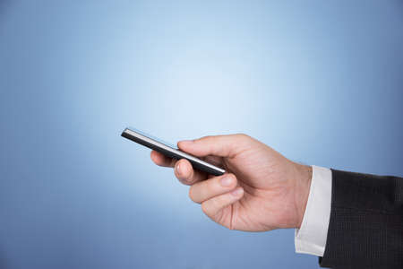 Hand holding mobile phone. Over blue background