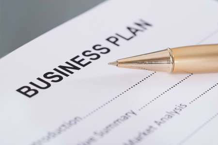 Business plan and golden pen. Closeup shot