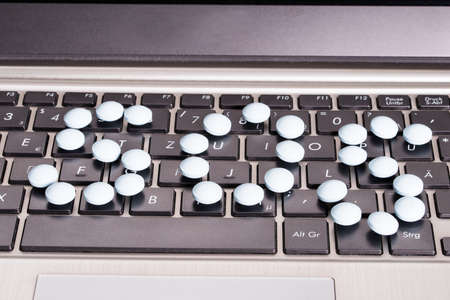 Pills on computer keyboard in online healthcare supportの写真素材