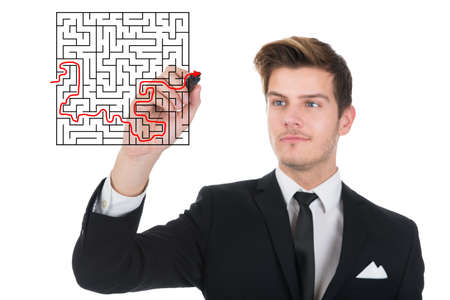 Young businessman solving maze puzzle on transparent screen over white backgroundの写真素材