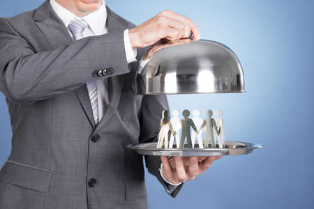 Butler holding tray and paper people. Over blue backgroundの写真素材