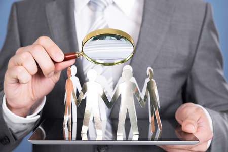 Holding magnifying glass and paper people. Closeup shotの写真素材