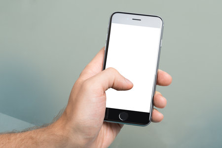Berlin; Germany - October 10; 2014: Cropped image of hand using an Apple iPhone6 with blank screen. Apple iPhone6 was launched on September 19; 2014のeditorial素材