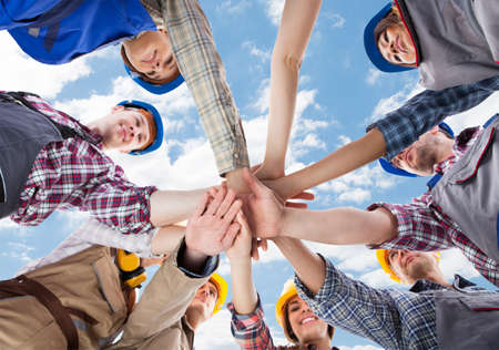 Directly below shot of multiethnic architects piling hands against skyの写真素材