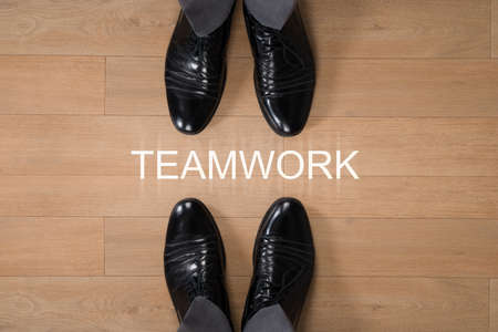 Directly above shot of businessmen standing with Teamwork written on hardwood floorの写真素材
